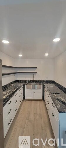 A modern kitchen with white cabinets and black countertops.