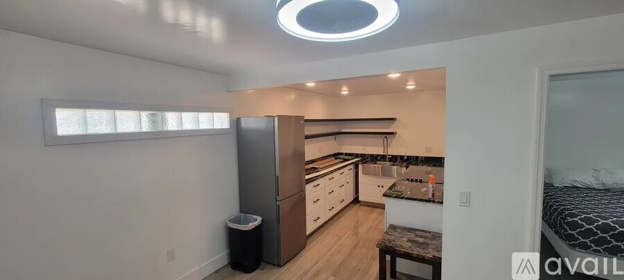 A kitchen with a refrigerator, cabinets, and a countertop with a sink.