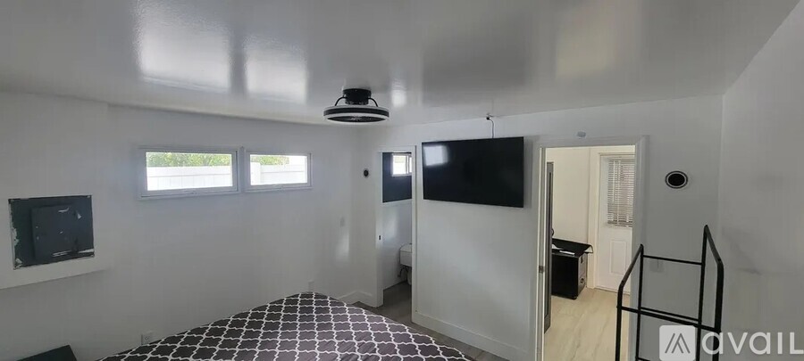 A bedroom with a bed, television, and a window.