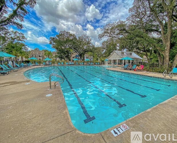 A large outdoor swimming pool surrounded by trees and a pavilion.