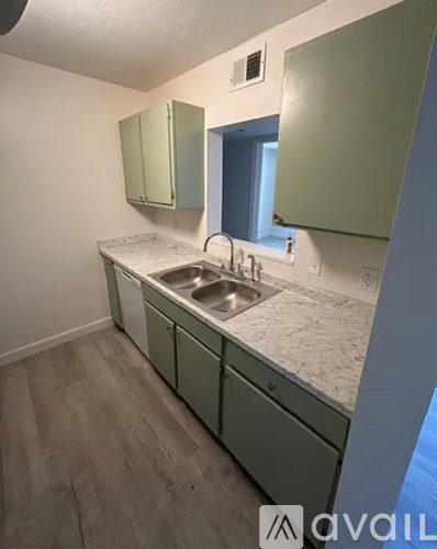 A kitchen with green cabinets and a white countertop.