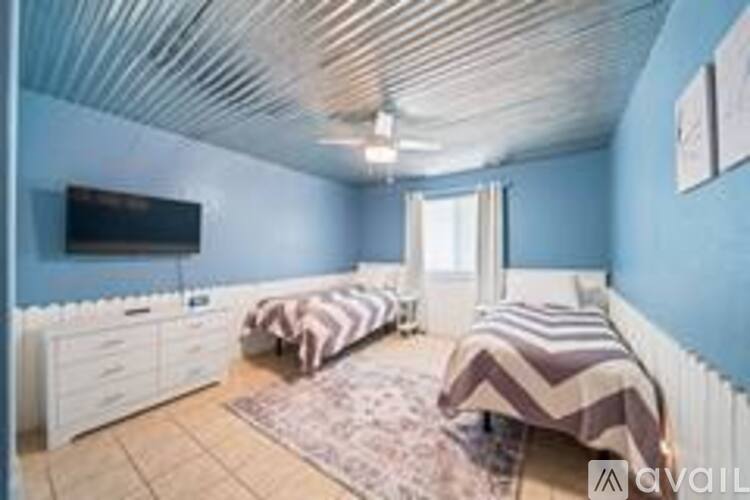 A bedroom with two beds and a television on the wall.