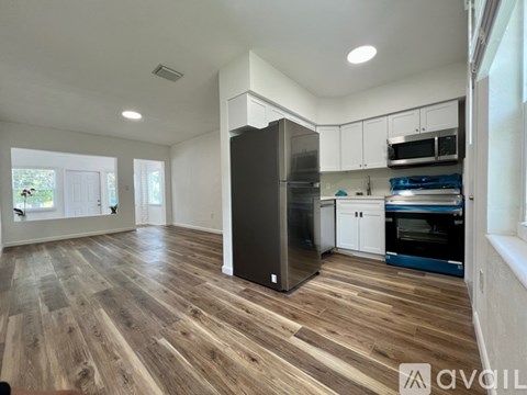 A kitchen with a black fridge and wooden floors.