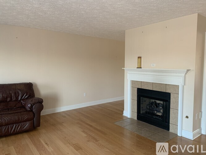 A living room with a fireplace and a brown leather couch.
