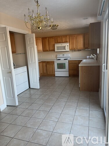 A kitchen with a white stove top oven and a chandelier.