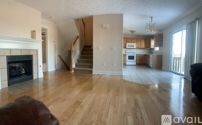 A living room with a fireplace and a staircase.