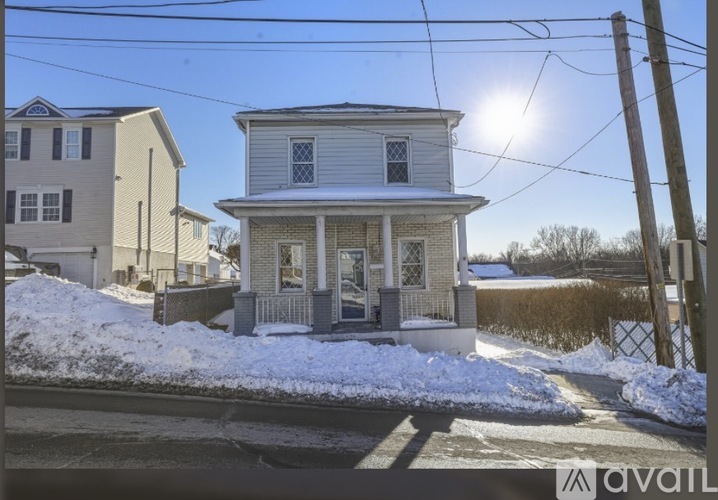 A house with a white front porch and a snow-covered ground.