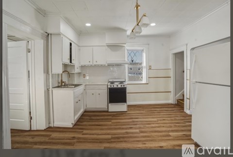 A kitchen with white cabinets and a wooden floor.