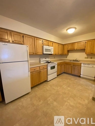A kitchen with wooden cabinets and a white fridge.