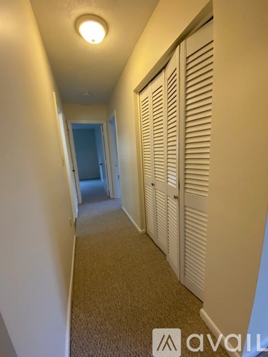 A hallway with white walls and carpeted floor.