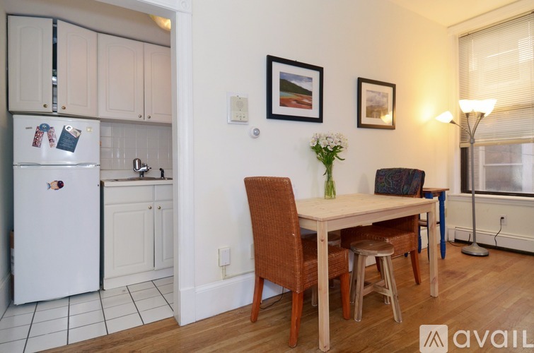 A kitchen with a white fridge and a dining table with chairs.