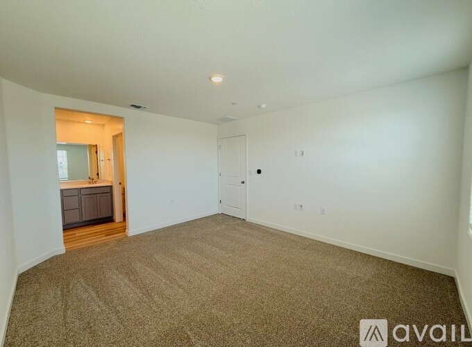 A spacious room with carpeted floor and white walls.