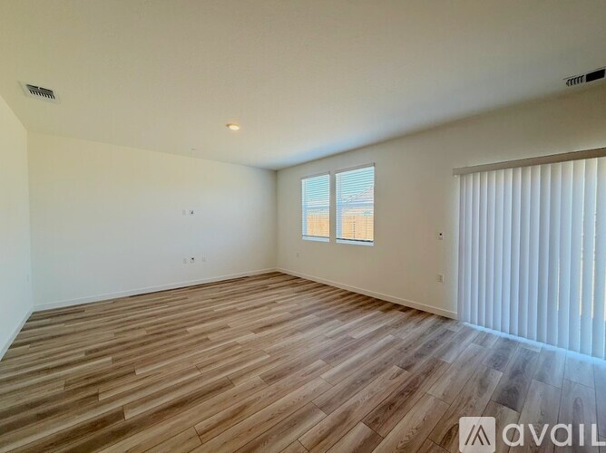 A room with wooden flooring and a window with blinds.