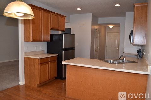 A kitchen with wooden cabinets and a black refrigerator.