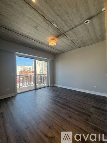 A room with a wooden floor and a window overlooking a cityscape.