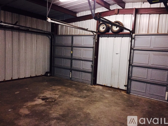 A garage with two doors, one open, and a metal beam overhead.