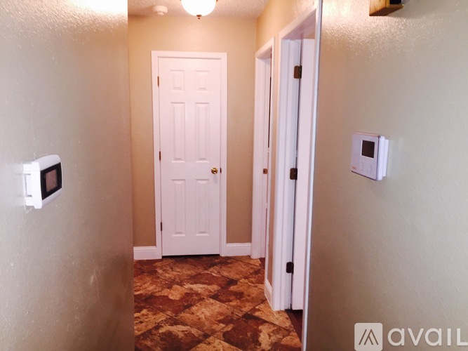 A hallway with a white door and a wall-mounted light fixture.