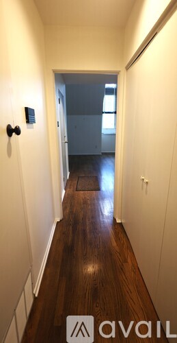 A hallway with a black door handle and a light switch on the wall.