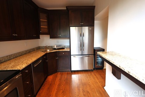 A kitchen with dark wood cabinets and a stainless steel refrigerator.