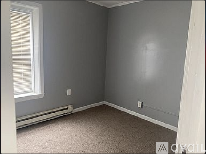 A room with a window and a carpeted floor.