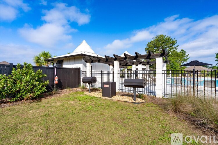 A white gazebo with a black roof is surrounded by a black fence and a mailbox.