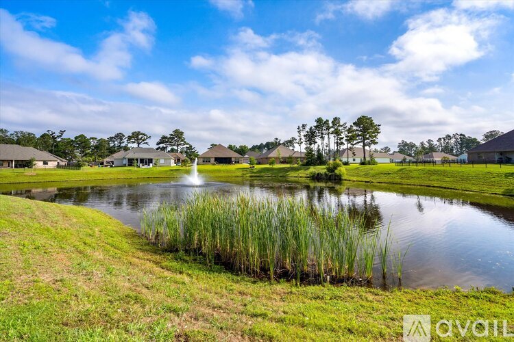 A serene landscape with a pond, grass, and a clear sky.