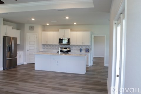 A kitchen with white cabinets and a wooden floor.