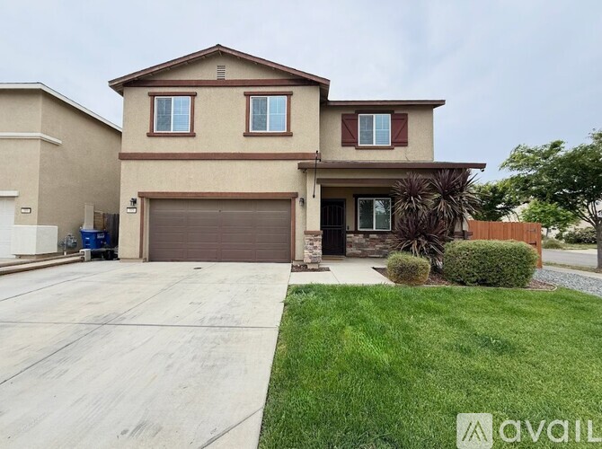 A beige house with a brown garage door and a driveway.