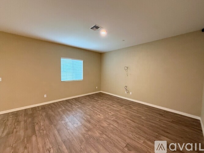 A room with wooden flooring and a window with blinds.