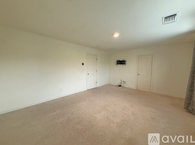 A spacious room with beige carpeting and white walls.