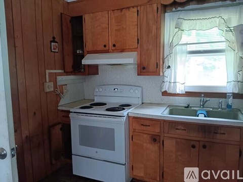 A kitchen with wooden cabinets and a white stove top oven.