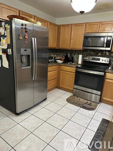 A kitchen with a refrigerator, microwave, oven and a rug on the floor.