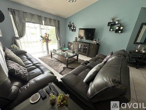 A living room with a black leather couch and a glass coffee table.
