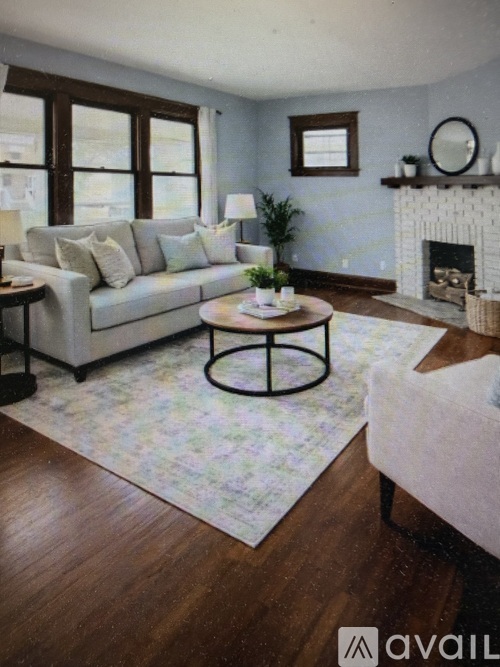 A living room with a white couch, a coffee table, and a fireplace.