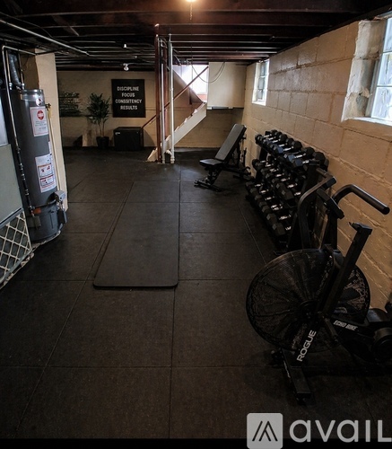 A gym with a row of dumbbells and a Rogue exercise bike.