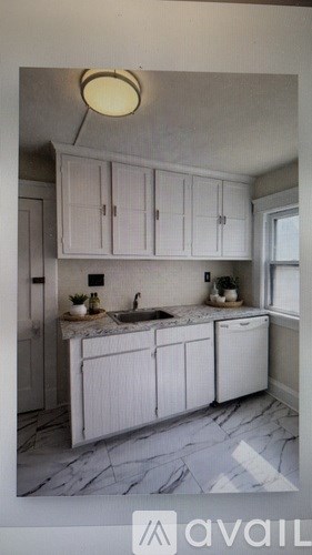 A kitchen with white cabinets and a marble countertop.