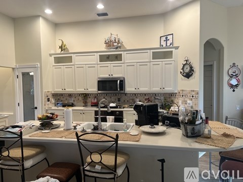 A kitchen with white cabinets and a countertop with a sink and a microwave.
