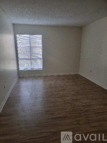 A room with wooden flooring and a window with blinds.