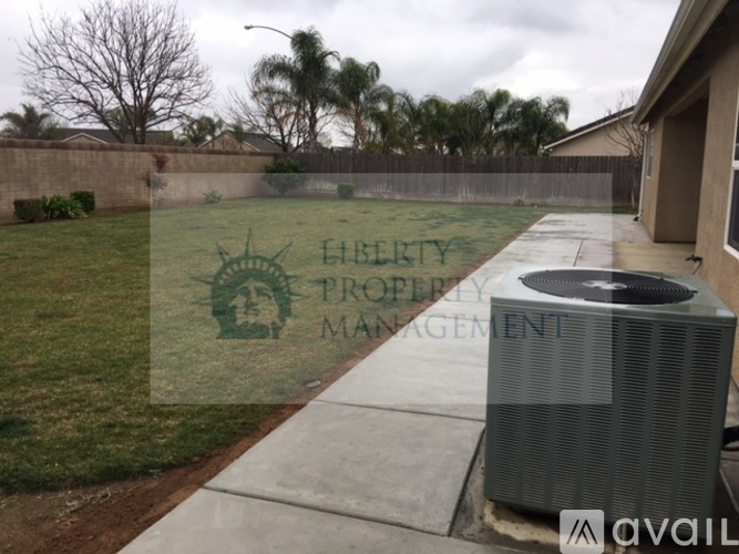 A black air conditioning unit is on a concrete slab in front of a house.