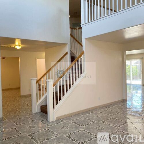 A spacious foyer with a tiled floor and a staircase leading to the upper level.