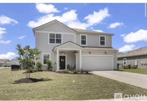 A two-story house with a garage and a tree in front.