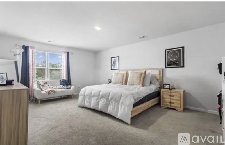A bedroom with a large bed and a window with curtains.