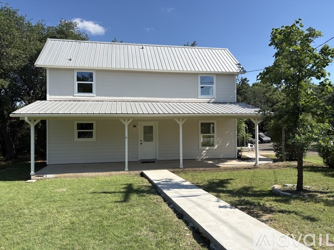A white house with a metal roof and a porch.