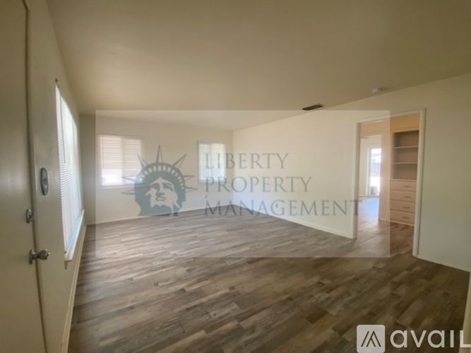 A room with wooden flooring and a wall that says "LIBERTY PROPERTY MANAGEMENT" with a logo of a woman's face and a star.