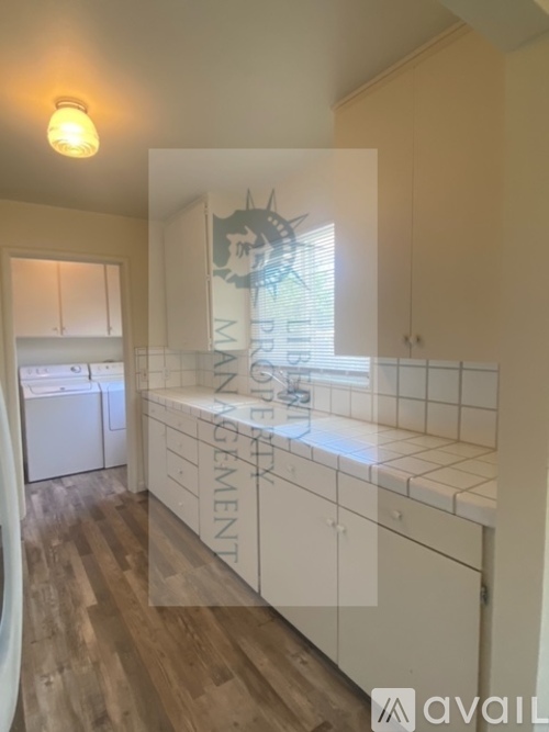 A kitchen with white cabinets and wooden floors.