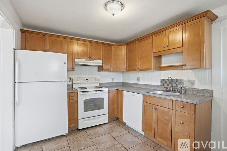 A kitchen with white appliances and brown cabinets.