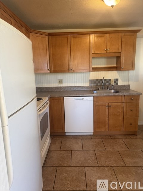 A kitchen with white appliances and brown cabinets.