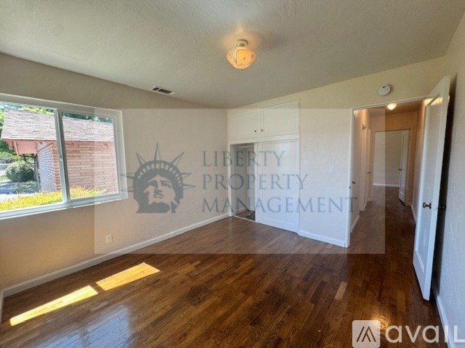 A room with wooden floors and a logo for Liberty Property Management on the wall.