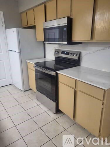 A kitchen with a white refrigerator, black oven, and beige cabinets.