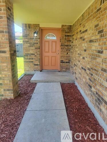A red door is at the end of a brick wall.
